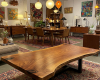 A long, boat-shaped live edge table with a gentle arc, featuring a prominent dark 'island' of grain at one end.