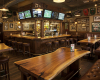 The lively atmosphere of a sports pub is enhanced by a unique live edge table and a classic, memorabilia-filled bar.