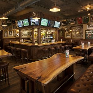 The lively atmosphere of a sports pub is enhanced by a unique live edge table and a classic, memorabilia-filled bar.