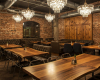 This custom restaurant interior juxtaposes industrial brick walls with the glamour of chandeliers and live edge tables.