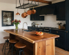 A luxury farmhouse kitchen's focus is a live edge waterfall island with a dramatic, rich suar wood grain.