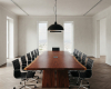 A commanding, boat-shaped live edge boardroom tabletop with a rich wood grain and a central, flush-mounted tech hub.