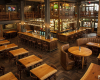 A grand, multi-level traditional pub featuring a long, solid wood bar, classic tables, and a mezzanine level.