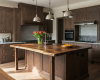 A luxury industrial loft kitchen is centered by a thick, solid slab live edge island with a rich suar wood top.