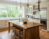 A luxury Tuscan-style kitchen is centered by a rustic live edge island with a thick, solid suar wood worktop.