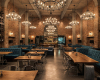 A grand, industrial-luxe restaurant where ornate chandeliers hang above bespoke live edge suar wood tables.