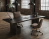 A commanding, single-slab executive desk with a dark, ebonized finish and a subtle live edge in a luxury office.
