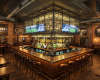 The grand interior of an upscale sports pub, featuring a custom straight-edged bar and solid wood tables.