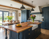 Luxury farmhouse kitchen with dark blue cabinets, a Belfast sink, and an adjoining live edge dining area.