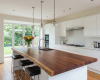 A bright, contemporary kitchen with a large live edge island that serves as a central breakfast bar with a sink.