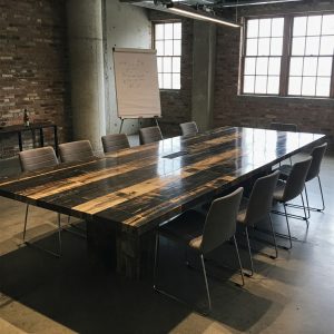 A 12-seater masterpiece conference tabletop made from petrified wood with a high-contrast striped pattern and a tech hub.