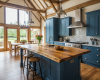 Luxury barn conversion kitchen with a vaulted ceiling, exposed beams, blue cabinets, and a rustic live edge island.