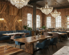 A luxury rustic-glam restaurant featuring bespoke live edge tables, wood wall paneling, and crystal chandeliers.