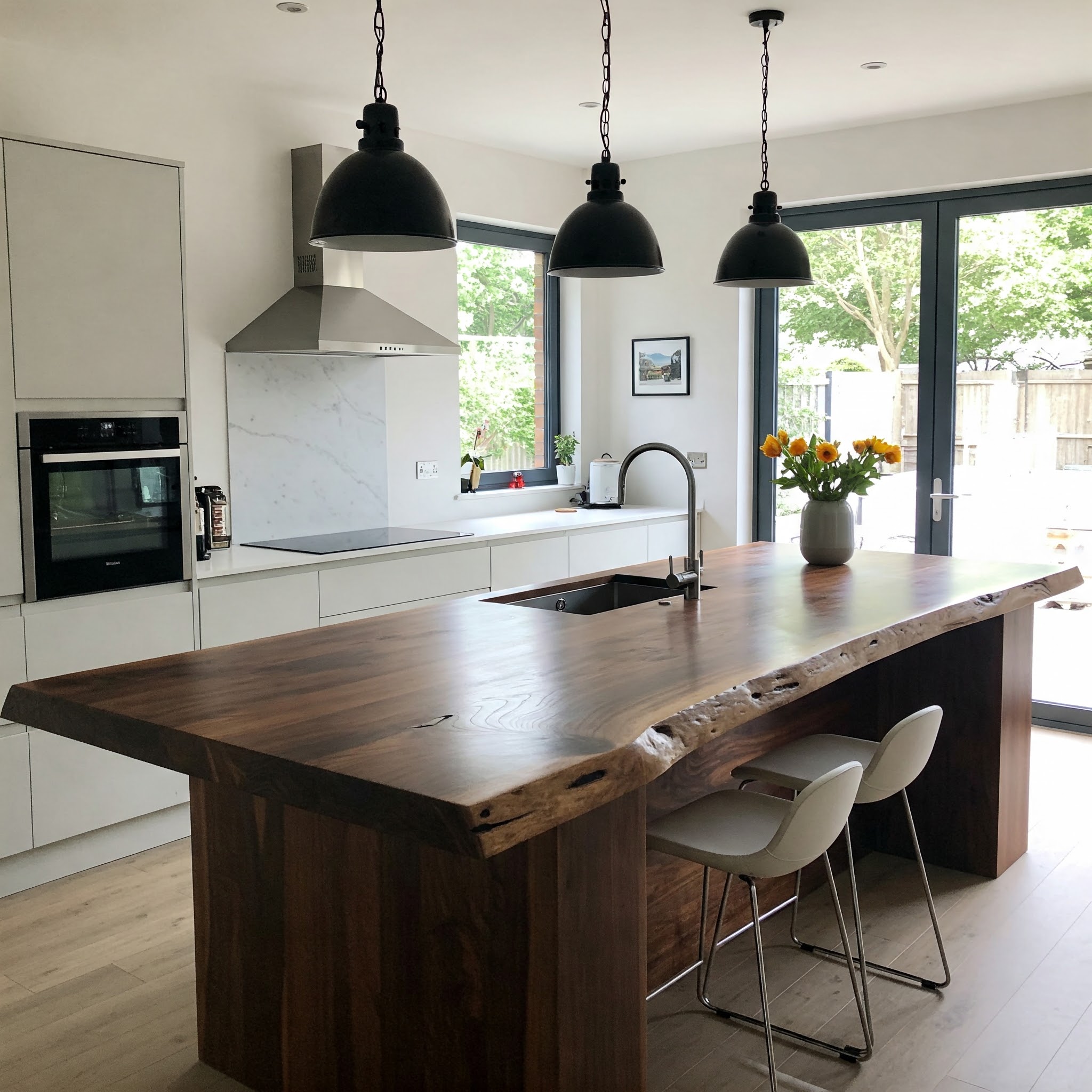 Bespoke live edge kitchen island with a thick, single-slab top and integrated sink in a luxury modern kitchen.