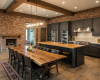 Luxury open-plan kitchen with exposed beams, charcoal cabinets, and a grand, rustic live edge dining table.