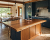Bespoke live edge breakfast bar with a thick, single-slab worktop, set within a luxury kitchen with blue cabinets.